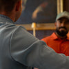 Two golfers in smart Oscar Jacobson polos and layers at a clubhouse, dressed within a typical golf dress code