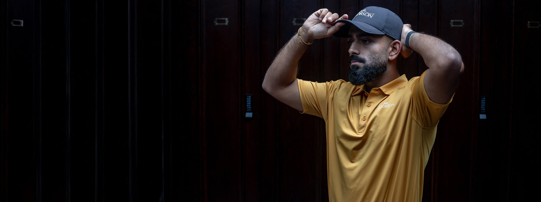 A golfer in an Oscar Jacobson polo, photographed against dark clubhouse panelling