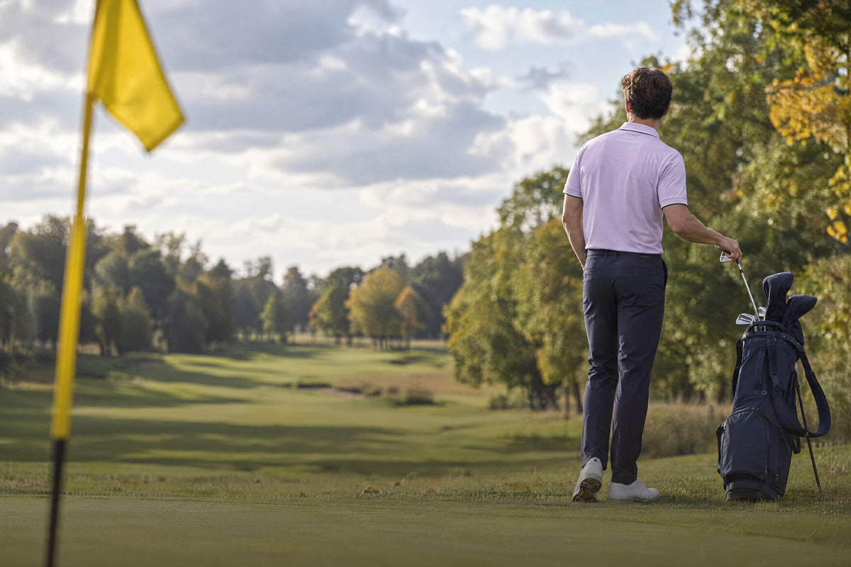 Man in a lavender Mallory polo looking out over an autumn golf course